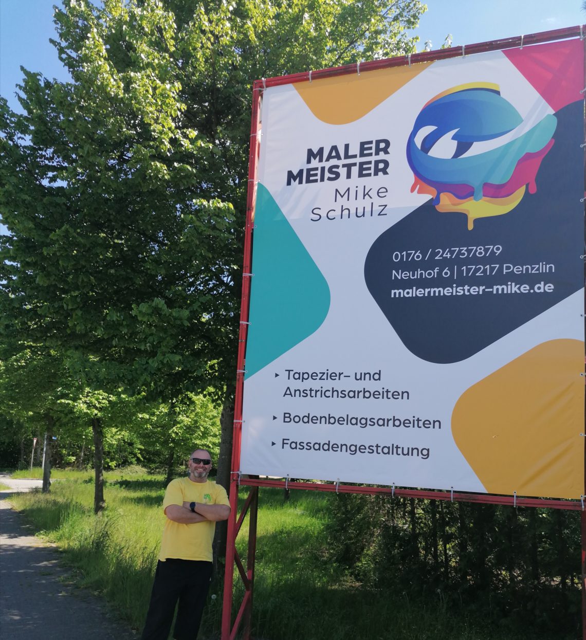 Mike Schulz neben seinem Werbeplakat am Bethanienberg in Neubrandenburg
